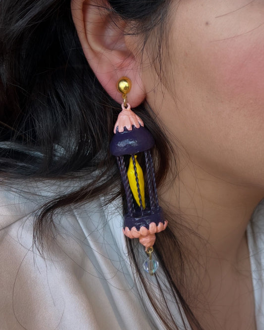 Yellow bird in a purple cage dangler