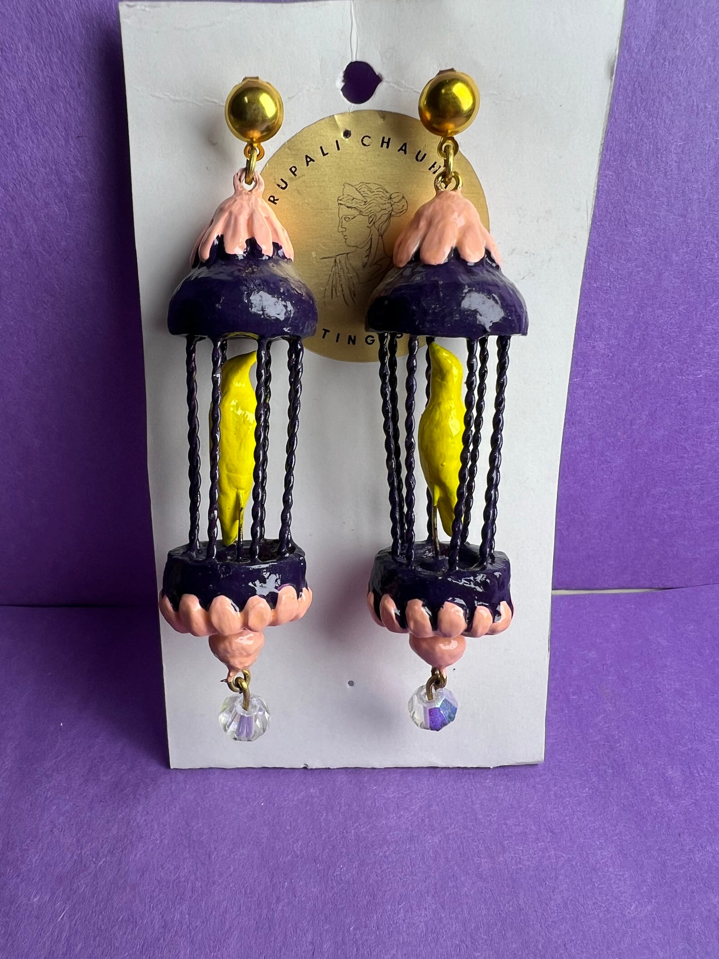 Yellow bird in a purple cage dangler