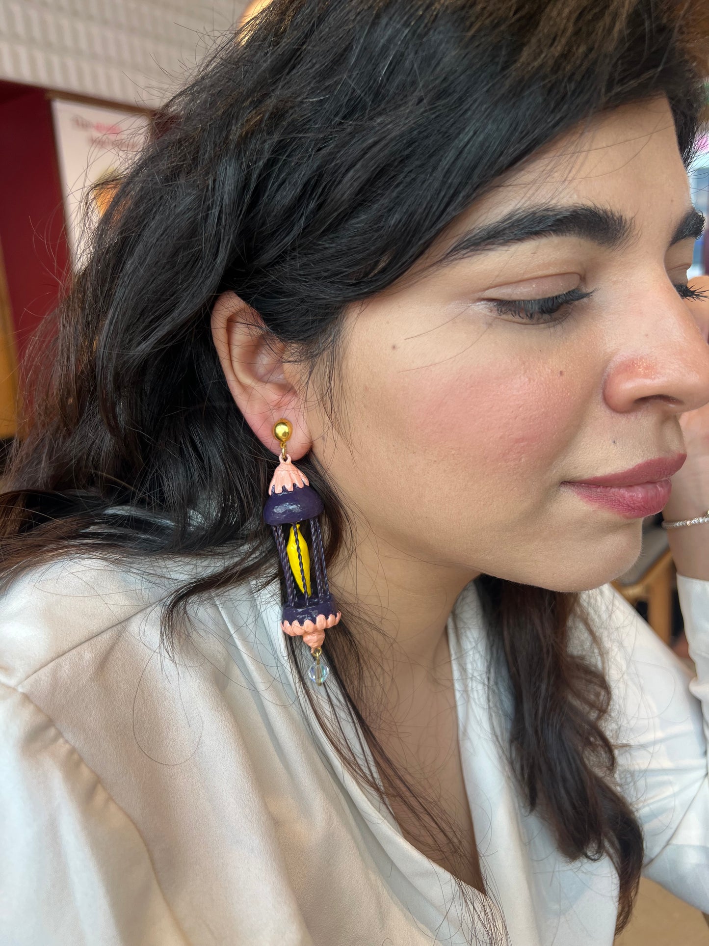 Yellow bird in a purple cage dangler